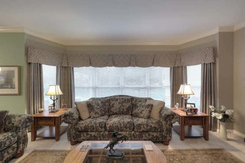 A custom living room valance frames larger windows for a diminutive accent that pairs elegantly with custom drapery. 