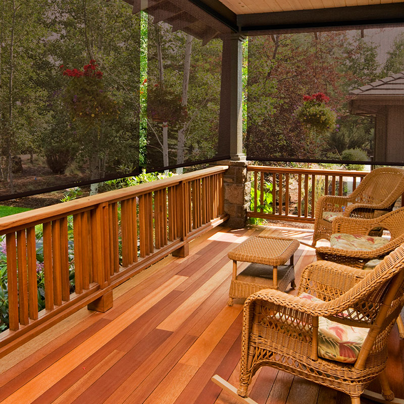 Outdoor wood patio enclosed with dark solar shade screens, providing glare reduction, UV protection, and clear views of the landscape.